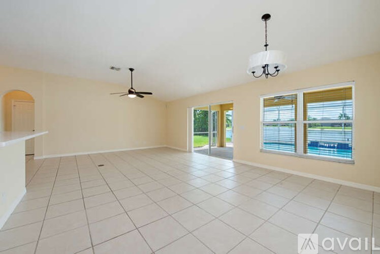 A spacious room with a ceiling fan and a chandelier.