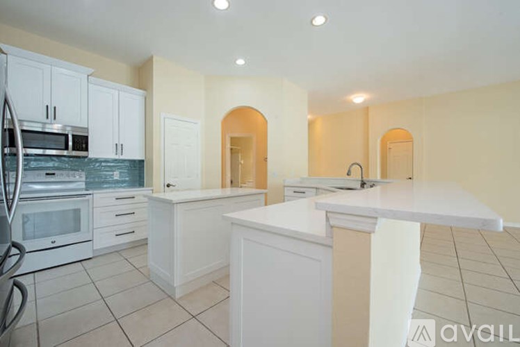 A kitchen with white cabinets and a white island.