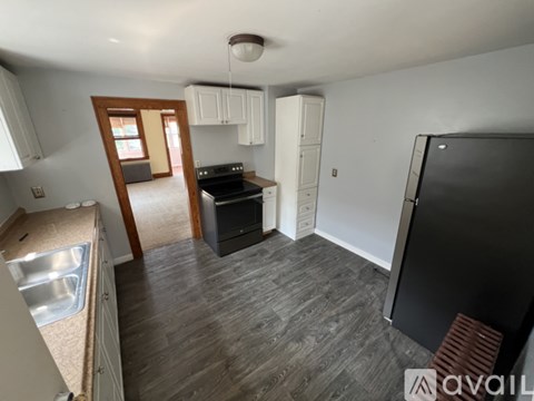 A kitchen with a black fridge and a black stove top.