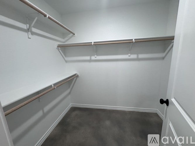 Empty walk-in closet with white walls and grey carpet.