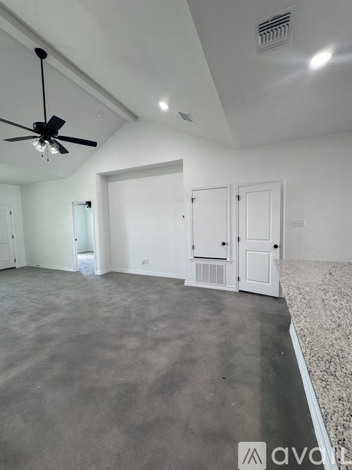 A room with a ceiling fan and a concrete floor.