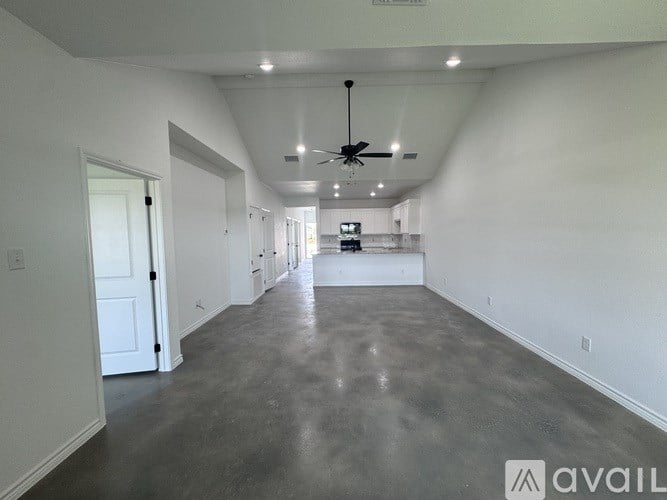 A spacious room with a ceiling fan and a long hallway.