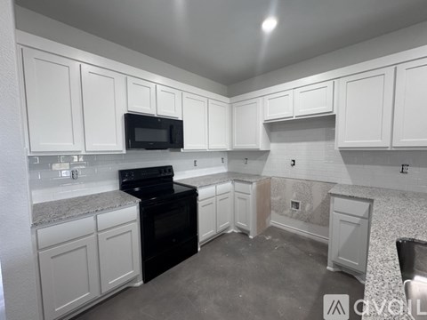 A kitchen with white cabinets and a black stove top oven.