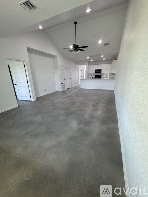 A spacious empty room with a ceiling fan and a door on the left.