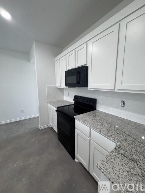 A kitchen with white cabinets and a black stove top oven.
