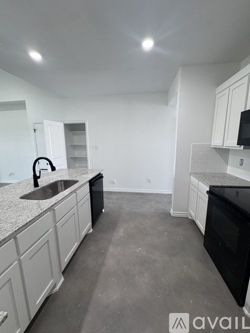 A kitchen with white cabinets and a black dishwasher.