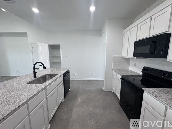 A kitchen with black appliances and white cabinets.