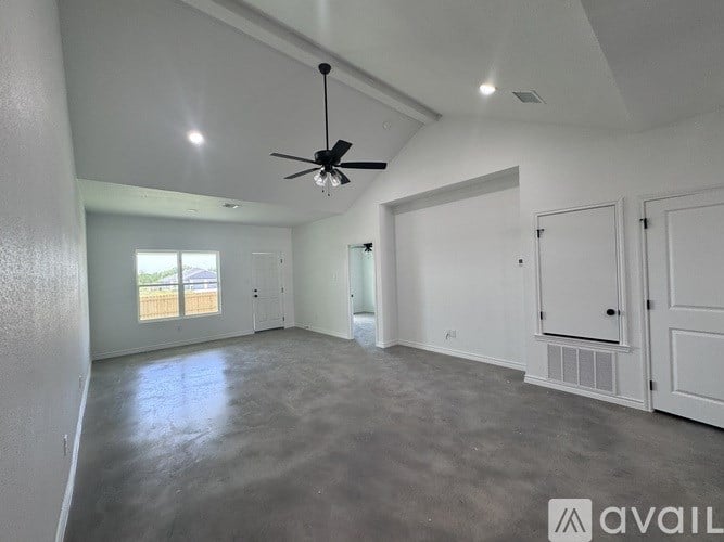 A spacious room with a ceiling fan and a large window.