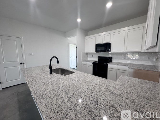 A kitchen with granite countertops and white cabinets.