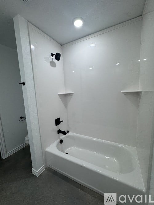 A white bathroom with a bathtub and a shower head.