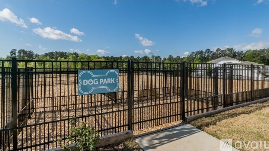 A dog park is enclosed by a black fence with a sign on it.