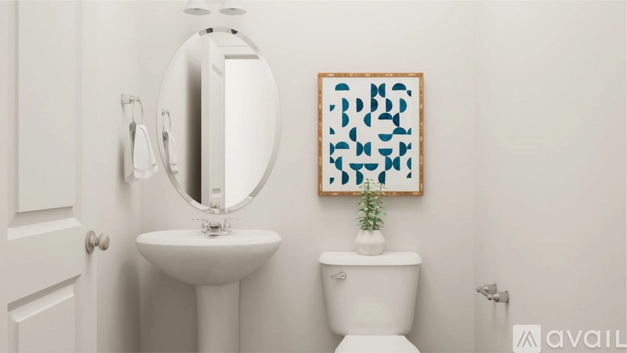 A bathroom with a toilet, sink, mirror and a picture on the wall.