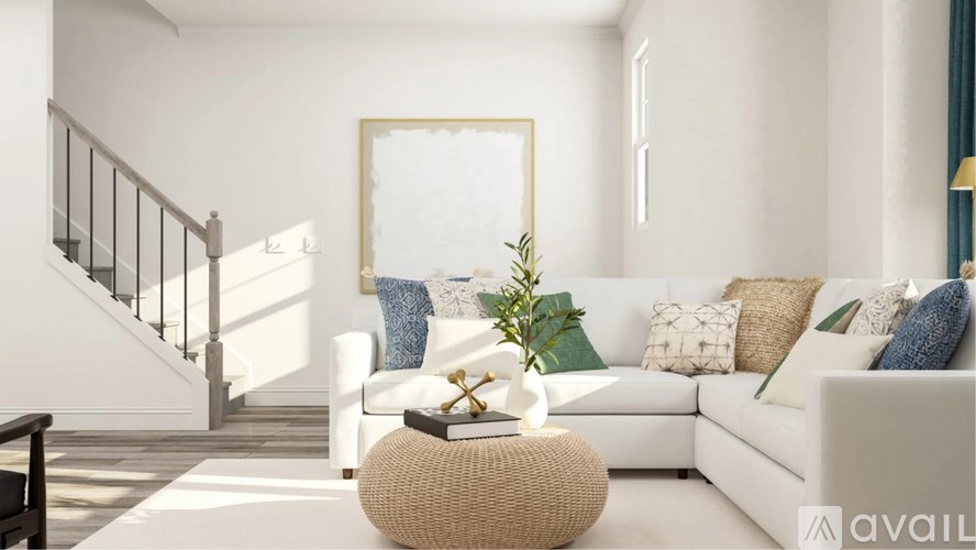 A living room with a white couch, a wicker table, and a staircase.