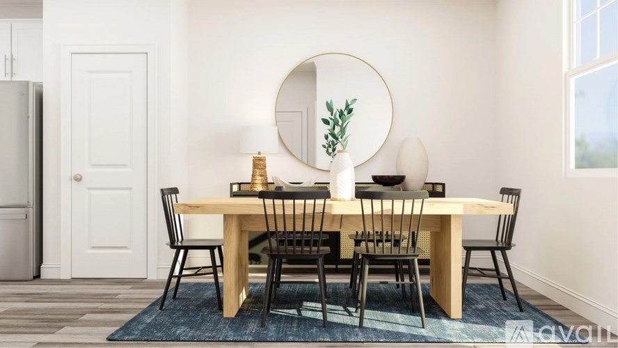 A dining table with chairs and a round mirror on the wall.