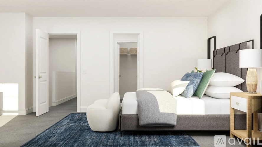 A modern bedroom with a large bed, two chairs, and a nightstand.