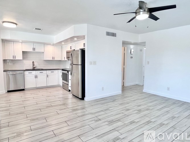 A spacious kitchen with a refrigerator, cabinets, and a ceiling fan.