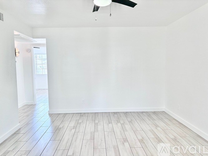 A room with a ceiling fan and wooden flooring.