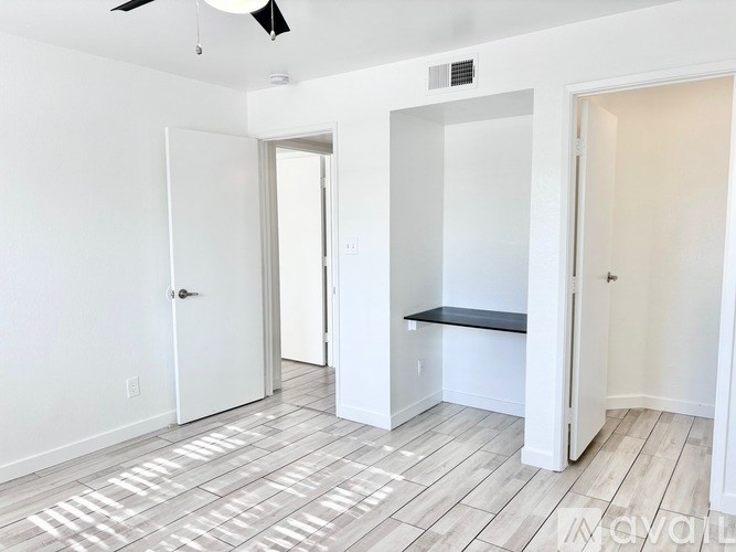 A room with a white door, a black bench, and a ceiling fan.