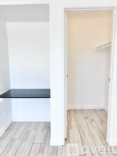 A white hallway with a bench and a door.