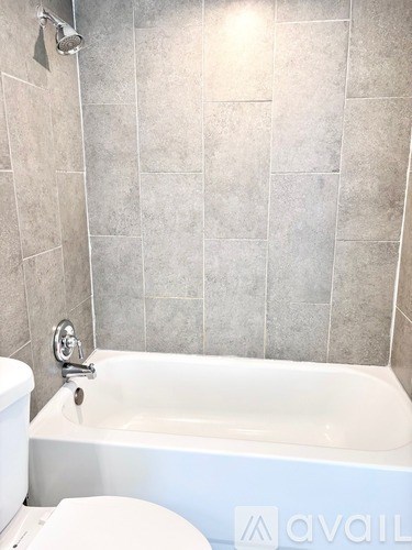 A white bathtub with a shower head above it.