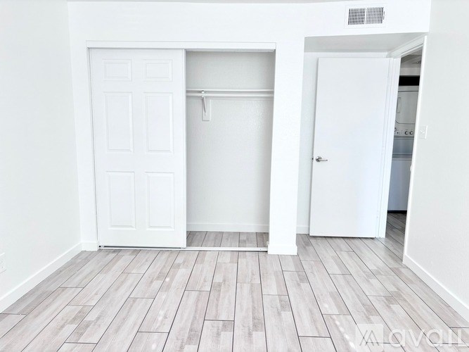A white door is open to a room with a wooden floor.
