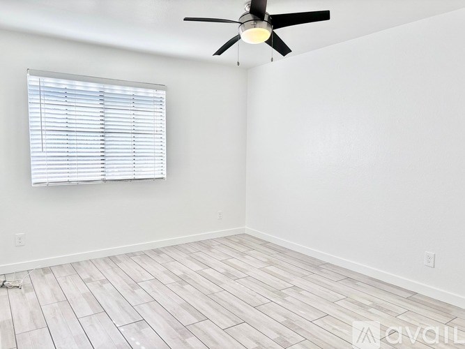 A room with a ceiling fan and a window with blinds.