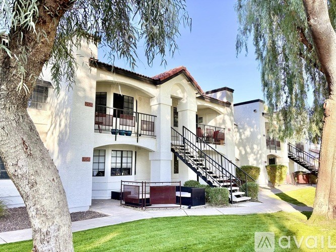 A white two-story house with a red roof and a balcony on the second floor.