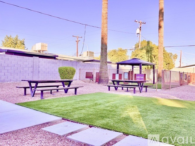 A gazebo sits in the middle of a grassy area with picnic tables on either side.