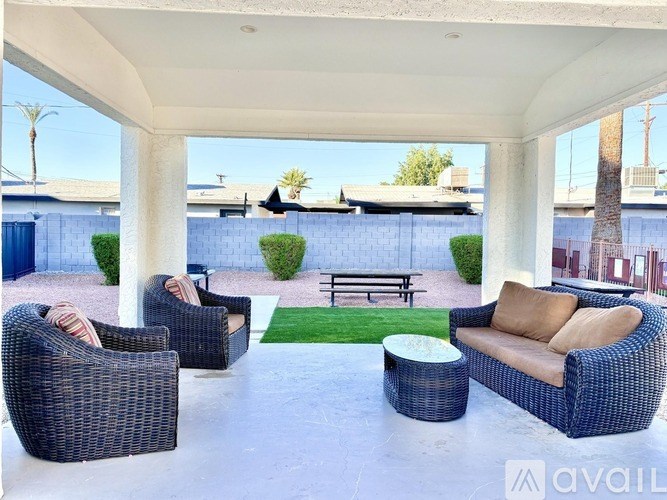 A patio with a wicker sofa, two chairs and a table.