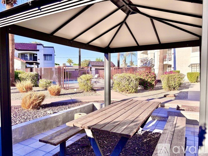 A patio with a table and benches under a white canopy.