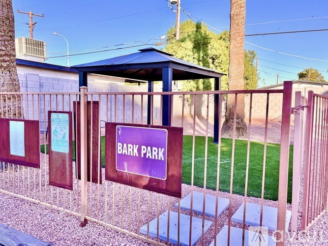 A sign that says Bark Park is on a fence.