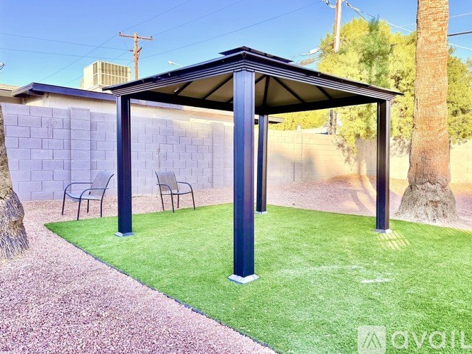 A covered patio area with a bench and a tree.