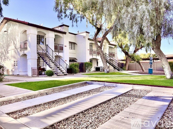 A white building with a red roof and a tree in front.