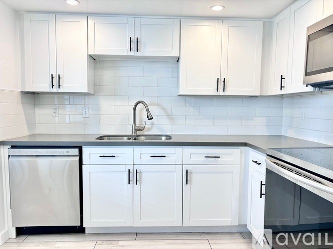 A kitchen with white cabinets and a black countertop.