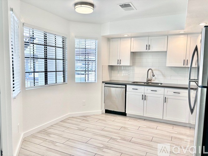 A kitchen with white cabinets and a wooden floor.