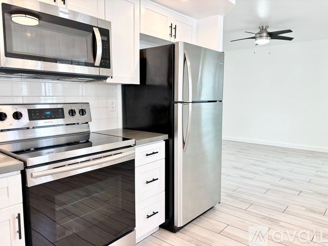 A modern kitchen with a stainless steel refrigerator, microwave, and oven.