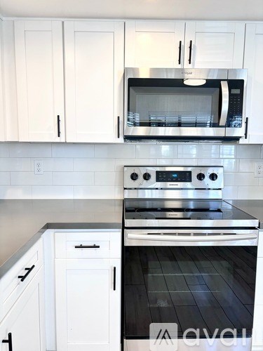 A kitchen with white cabinets and a stove top oven.