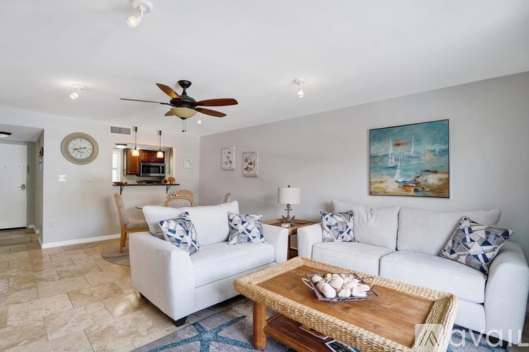 A living room with a white couch and a painting on the wall.