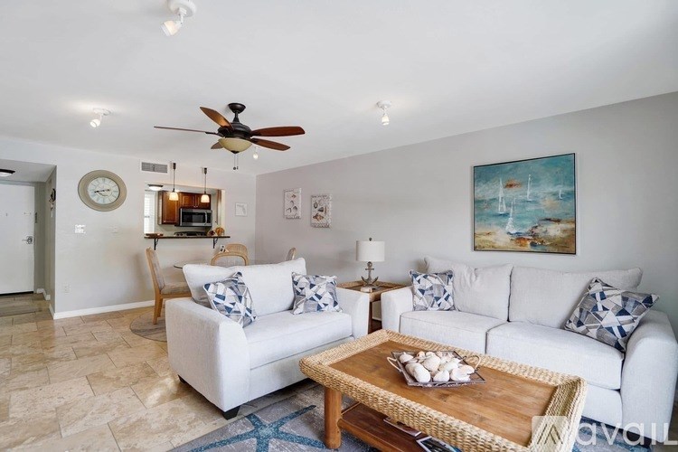 A living room with a white couch and a painting on the wall.