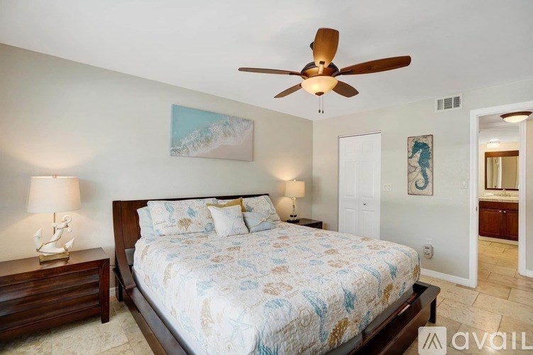 A bedroom with a bed, two lamps, and a ceiling fan.