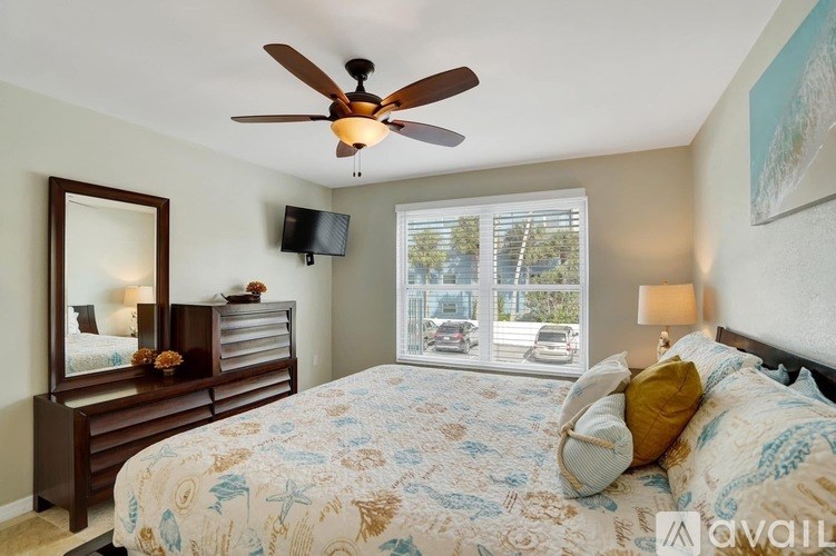 A bedroom with a bed, a dresser, a mirror, and a ceiling fan.