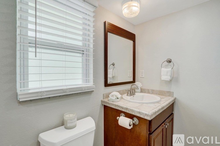 A bathroom with a toilet, sink, and a mirror.