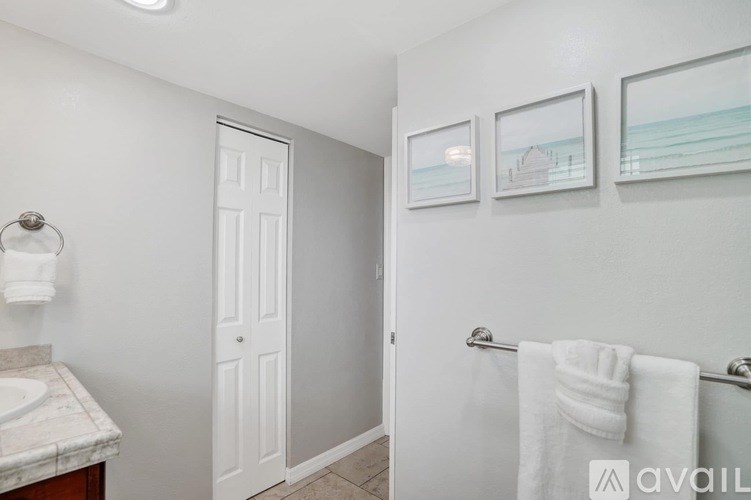 A bathroom with a white door, a towel rack with two white towels, and two pictures on the wall.