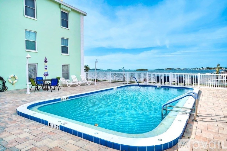 A small pool in a backyard with a table and chairs.