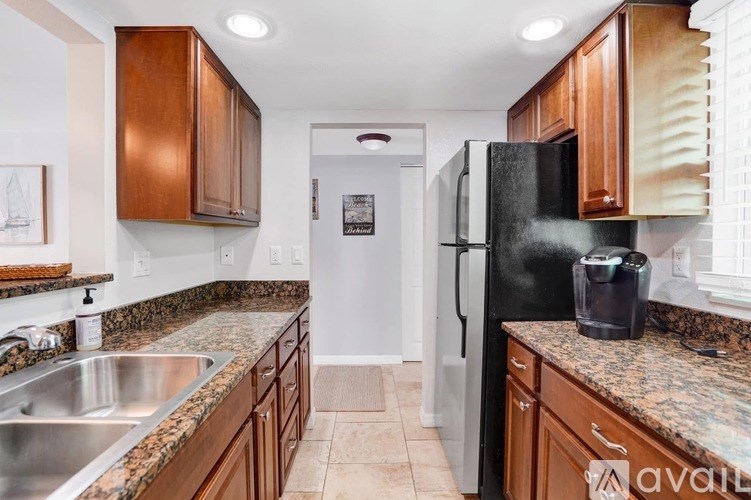 A kitchen with brown cabinets and a black refrigerator.