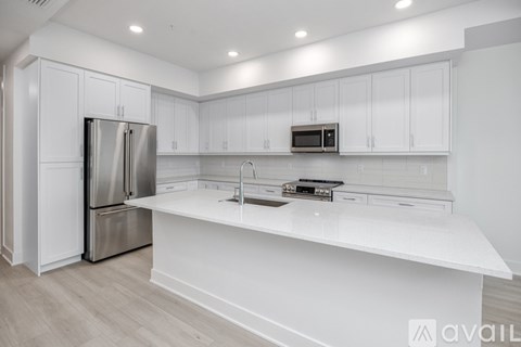 A modern kitchen with white cabinets and a stainless steel refrigerator.