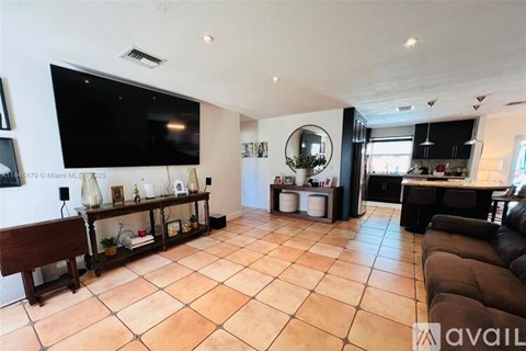 A living room with a brown couch and a flat screen TV mounted on the wall.