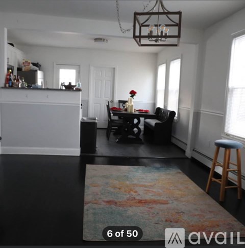 A living room with a black couch and a rug.