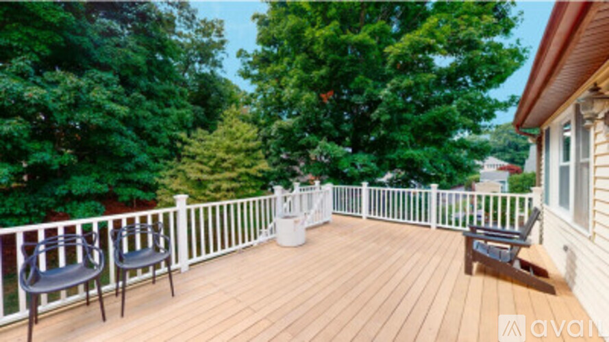 A deck with chairs and a table surrounded by trees.