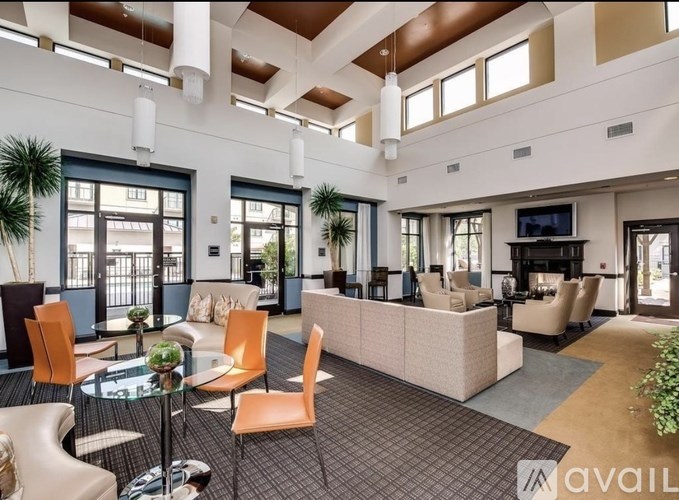 A spacious living room with a glass table and orange chairs.
